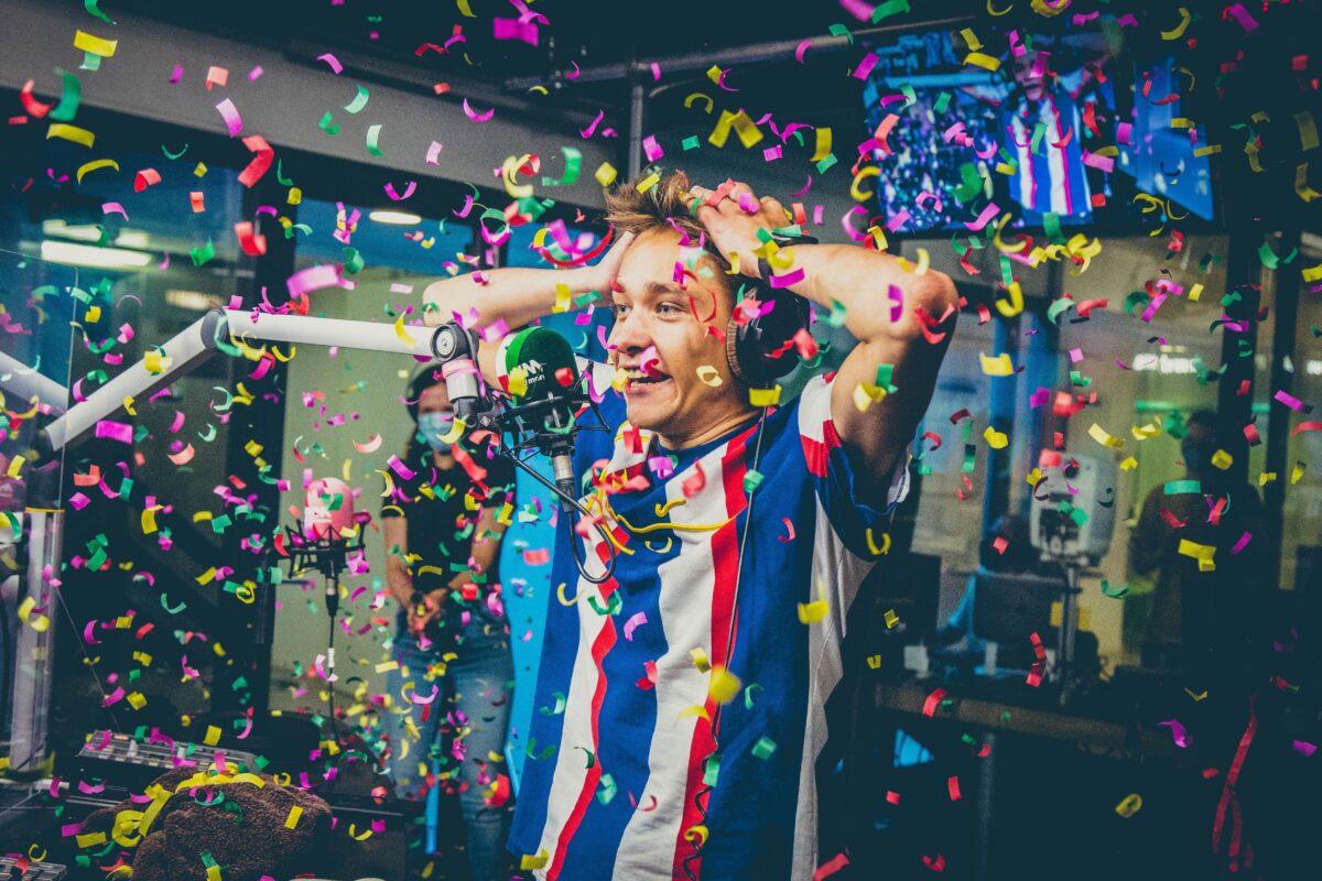Voltage in a radio studio with his hands on his head as confetti rains down