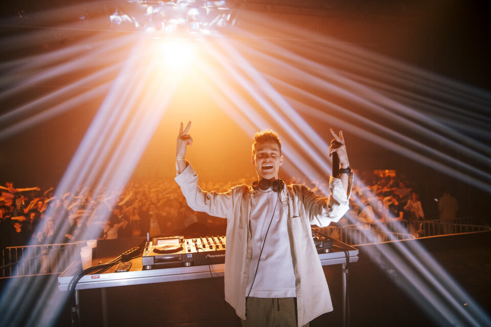 Voltage at the decks making peace signs, light beams fanning out over the crowd