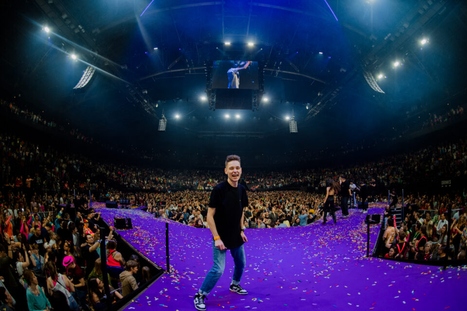 Voltage laughing on a confetti-covered purple catwalk in a packed arena